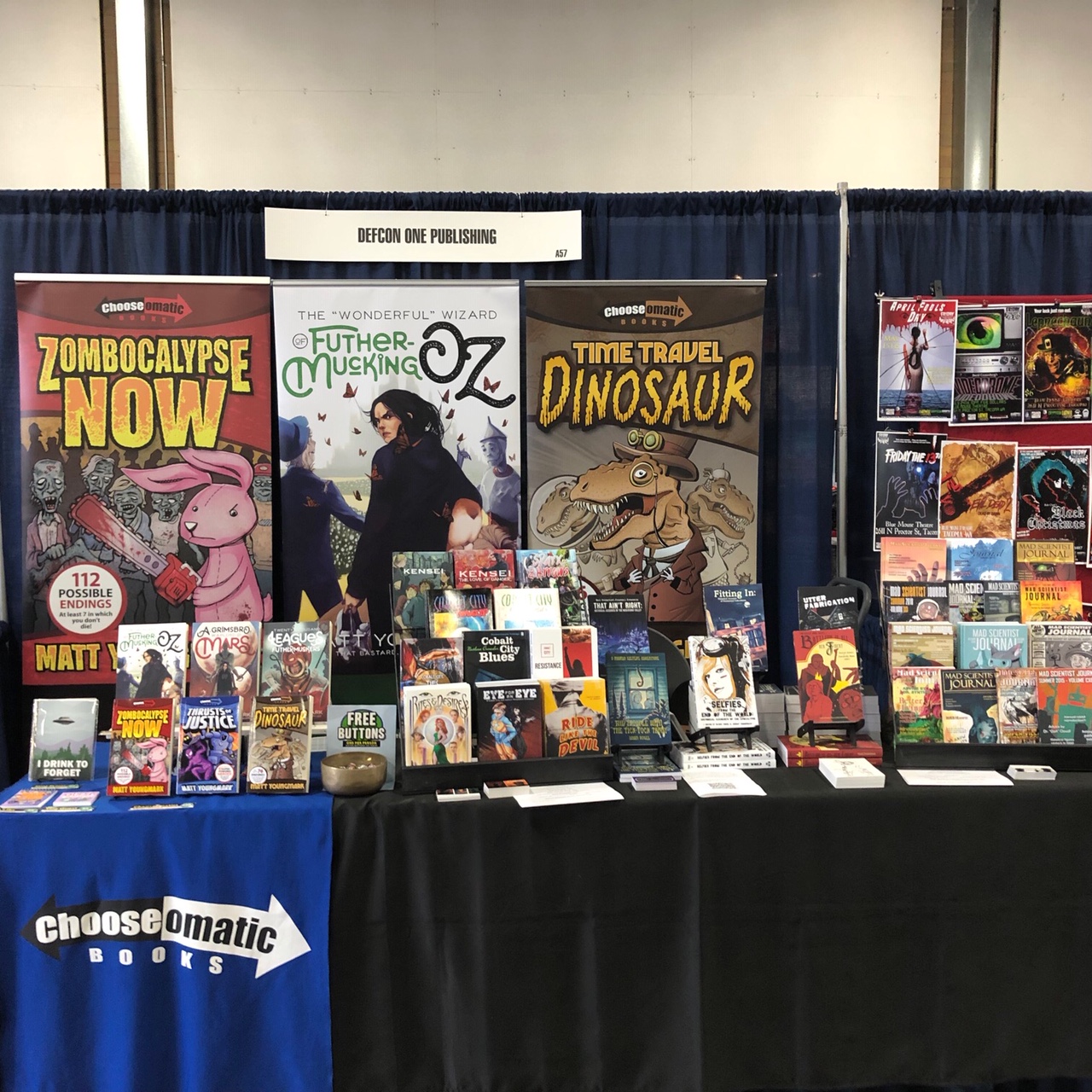 Convention table displaying books from Matt Youngmark and DefCon One