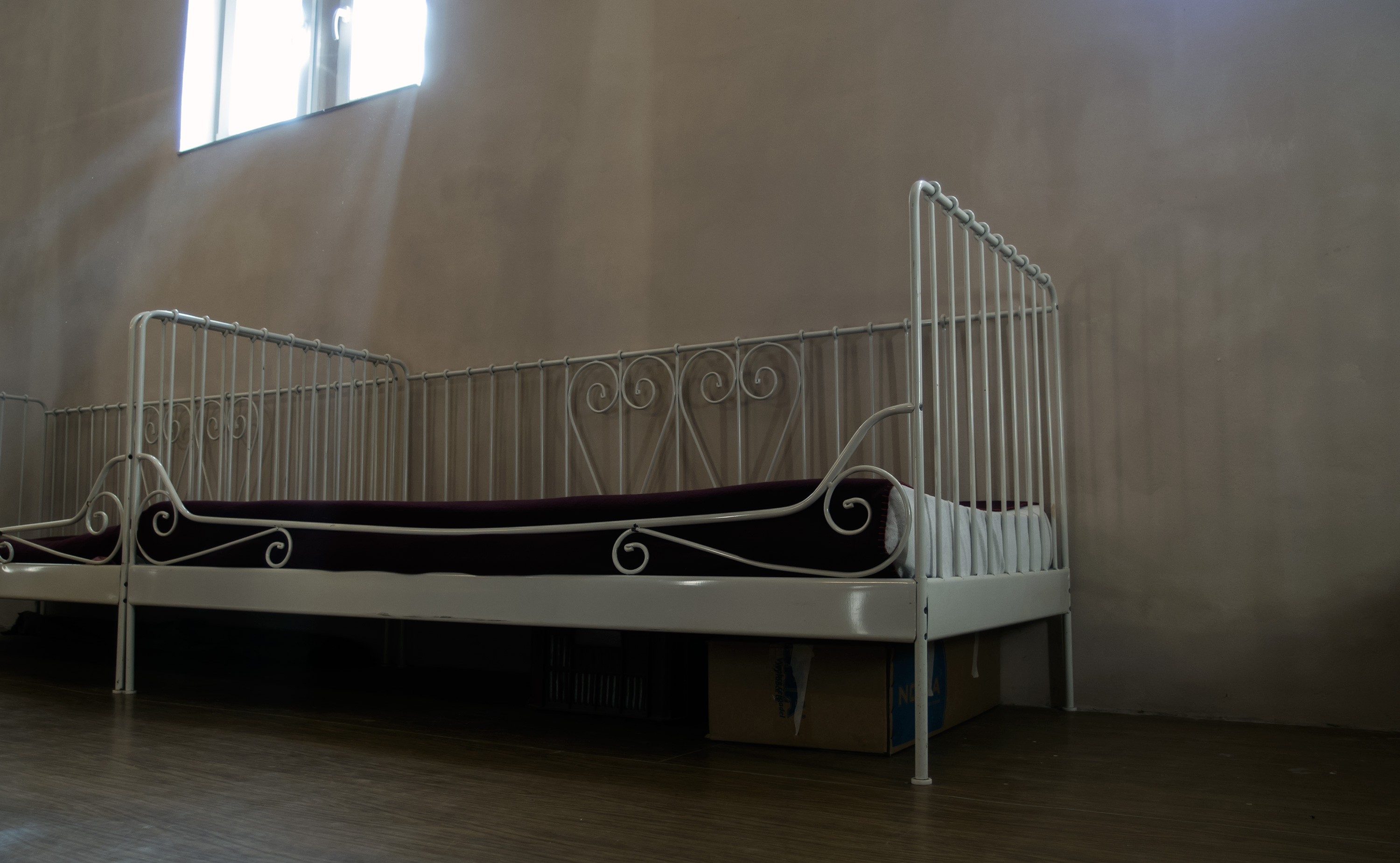 Simple empty bed with white metal railing on three sides